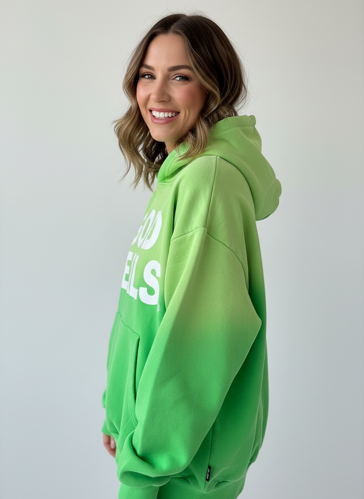 Hoodie ‘God Heals’ voor dames, christelijke streetwear-mode tegen een lichtgrijze achtergrond.